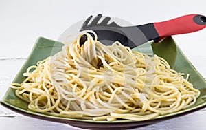 Al dente spaghetti pasta on a plate with pasta fork on white background