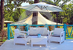 Al fresco cafe with white rattan wicker armchairs and tables on