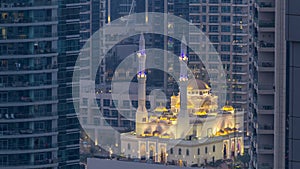Al Raheem mosque between skyscrapers day to night timelapse on the marina walk in Dubai Marina, Dubai, UAE. photo