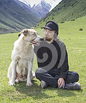 Alabai breed dog with a young guy on the background of the Alpine mountains, a pet friendship with a man