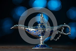 Aladdin`s magical genie lamp on soft blue lights background. Lamp of wishes concept. Antique arabian style