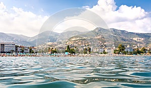 Alanya beach view from water and mediterranean sea. Unrecognizable crowd of people swimming. Tourism and holiday in Turkey.