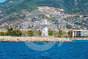 Alanya lighthouse on Alanya houses, beaches and mountain hills background at sunny day. Old lightshouse Alanya sea photo
