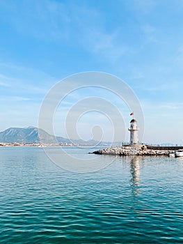 ALANYA, TURKEY - June 12,, 2021: Beautiful waterscape with white lighthouse under blue sky in summer day.