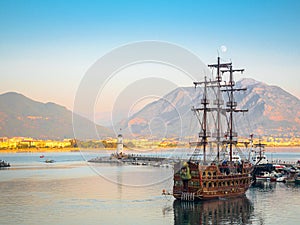 Alanya, Turkey. Pirate sailing pleasure cruise ship in the bay with a lighthouse in the evening. Vacation background