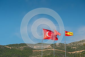 Alanya, Turkey. Red flags of Turkey on background of blue sky and mountains. Vacation postcard background