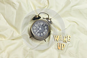 Alarm 7 o` Clock on white sheet bed with wake up wooden