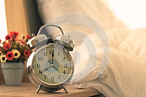 Alarm clock, analog vintage antique on table beside the bed