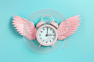 Alarm clock with angel wings flying on pastel background. Time flies concept, time management, free time. Time of flight. Day