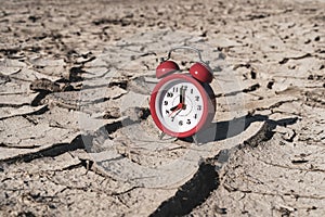Alarm clock on arid cracked soil