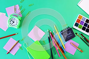 Alarm clock, Art materials and stationery on a green background, top view, back to school