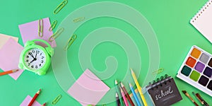 Alarm clock, Art materials and stationery on a green background, top view, back to school