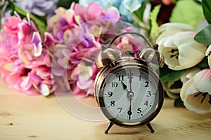 Alarm clock and artificial flowers bouquet with space background