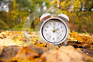 Alarm clock with autumn foliage, end of daylight saving time in fall, winter time changeover photo