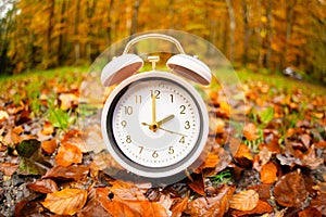 Alarm clock with autumn foliage, end of daylight saving time in fall, winter time changeover photo