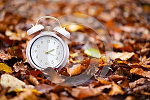 Alarm clock with autumn foliage, end of daylight saving time in fall, winter time changeover photo
