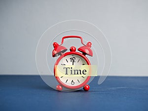 Alarm clock and beautiful spring flowers on blue table, space for text. Time change concept