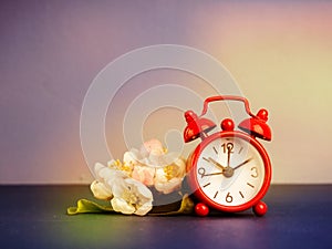 Alarm clock and beautiful spring flowers on blue table, space for text. Time change concept