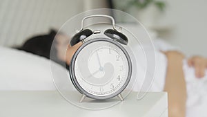 Alarm clock with beautiful young asian woman sleep in the morning to waking up in the bedroom