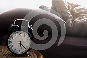 Alarm clock on bedside table made of wicker in vintage tone