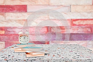alarm clock and books on stone shelf in library school concept with brick wall blur background
