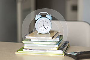 Alarm clock, books on table. Time management