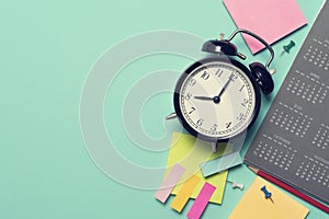Alarm clock and calendar on the green table background, planning for business meeting or travel planning concept