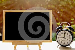 Alarm clock and chalkboard or blackboard in the public park for your text board plan with time concept