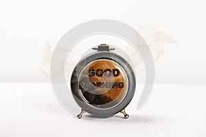 Alarm clock with coffee in and smoke vapour coming out and good morning with coffee bean texture on a white background