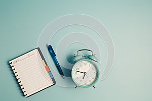 An alarm clock with a diary notebook and others work and educational materials