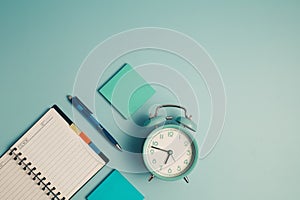 An alarm clock with a diary notebook and others work and educational materials