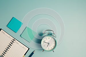 An alarm clock with a diary notebook and others work and educational materials