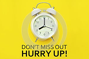 Alarm clock with Don`t miss out hurry up text on yellow background