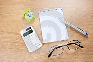 Alarm clock with empty notepad and pen on desk