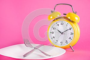 Old Alarm Clock and Empty Plate: Food and Chrono Nutrition Diet Concept photo