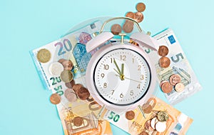 Alarm clock with Euro banknotes and coins, inflation, recession and financial crisis, high living cost