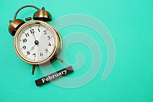 Alarm clock and February calendar with space copy on green mint background