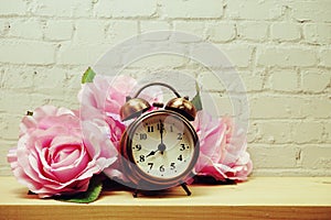 Alarm clock with flower decorative on white brick wall background