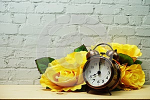 Alarm clock with flower decorative on white brick wall background