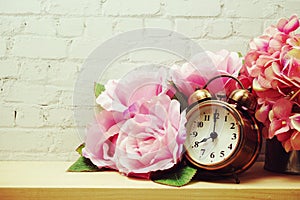 Alarm clock with flower decorative on white brick wall background
