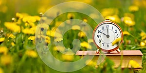 Alarm clock in the flowers in spring, daylight savings time banner