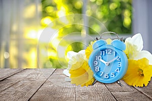 Alarm clock and flowers on table against background, space for text. Spring time