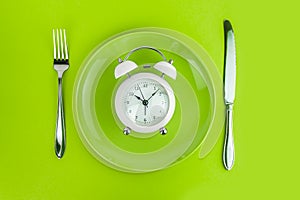 Alarm clock with fork and knife on the table. Time to eat, Breakfast, Lunch Time and Dinner concept