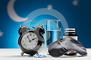 alarm clock, glass of water and sleeping pills