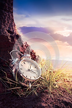 Alarm clock on grass at sunset or sunrise/ time concept