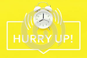 Alarm clock with hurry up text on yellow background
