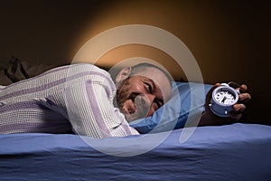 Alarm clock for a man who lies on the bed and smiles. Ease of waking up, good sleep, the right mode for