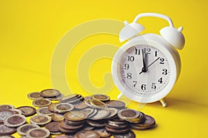 Alarm clock and money coin on yellow background,finance concept,business background, retirement, finance and saving money for