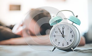 Alarm clock in the morning. Young man sleeps in the blurry background