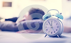 Alarm clock in the morning. Young man sleeps in the blurry background